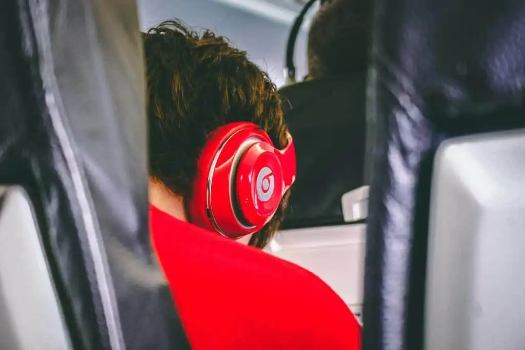 Passenger with red headphones sitting on an airplane.