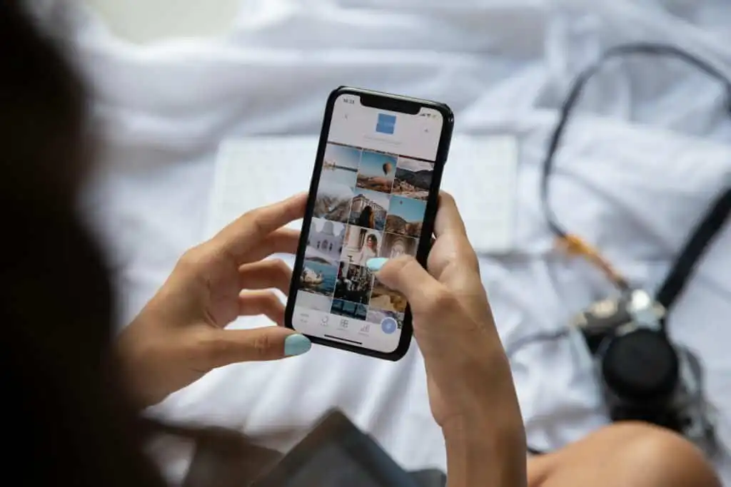 Person taking travel photos on smartphone in bed, showcasing travel memories.