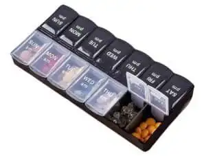 Medication organiser with weekly compartments and pills inside.