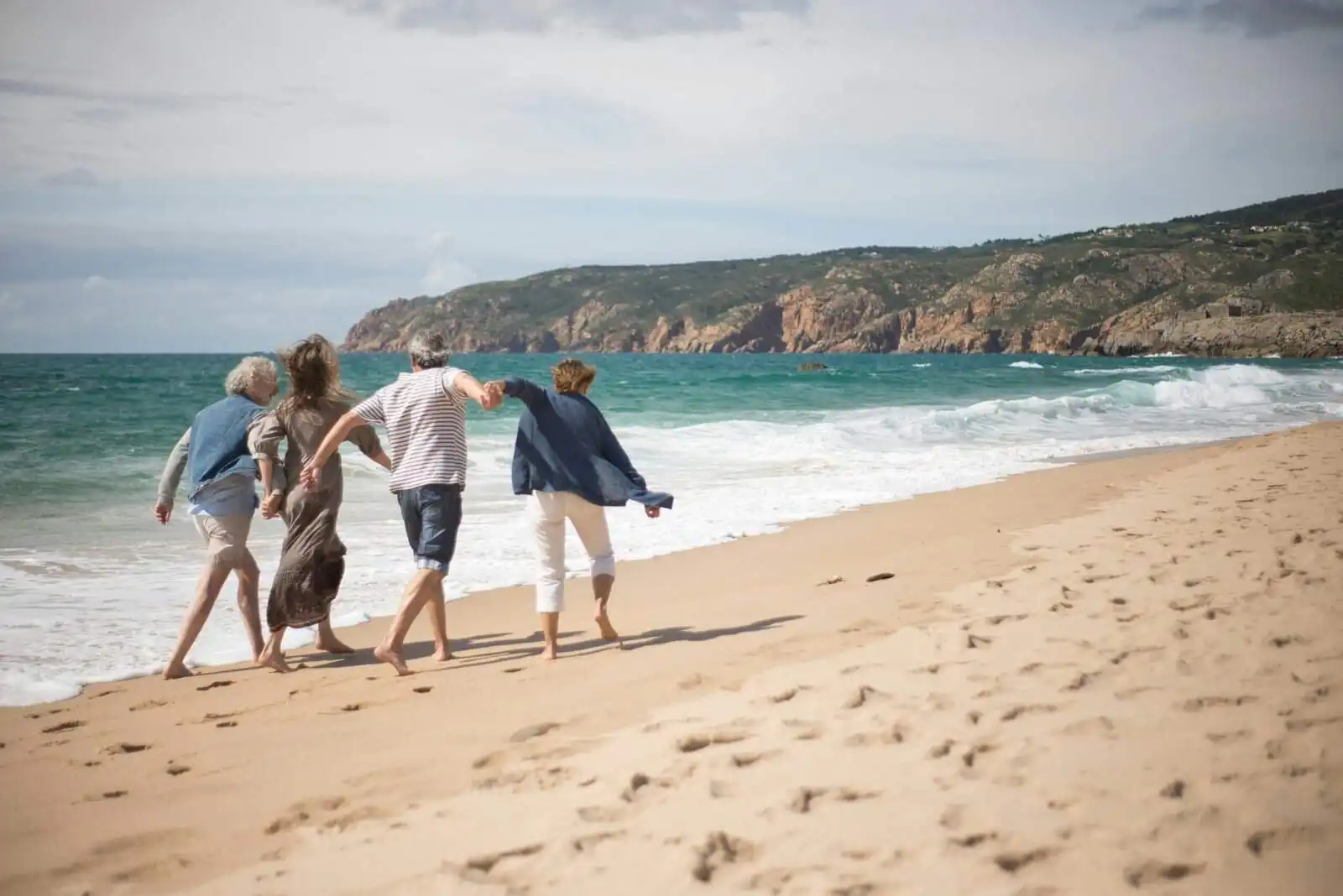 Family walking along the shoreline on a sunny day at Cornwall beach.