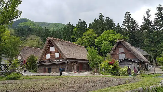 Style houses in Shirakawa-go village with lush greenery and mountain backdrop.