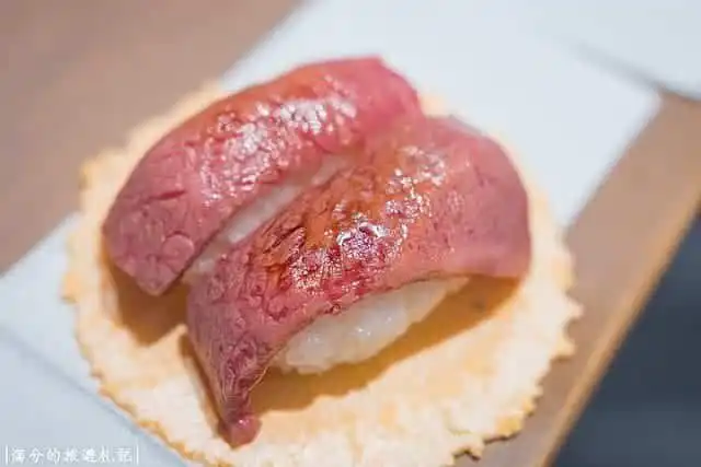 Fresh Wagyu beef sushi with rice on a wooden board.
