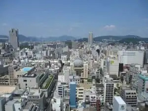 Aerial view of Hiroshima cityscape with buildings and mountains in the background.