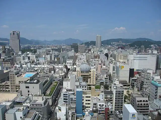 Aerial view of Hiroshima cityscape with buildings and mountains in the background.