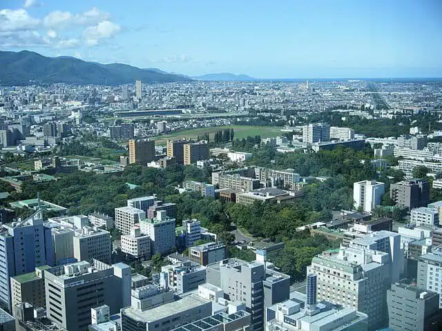Vibrant city skyline with lush green parks and modern buildings in Hokkaido, Japan.