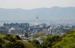 Kyoto skyline featuring Kyoto Tower with lush green foreground and distant mountains in the backgrou.